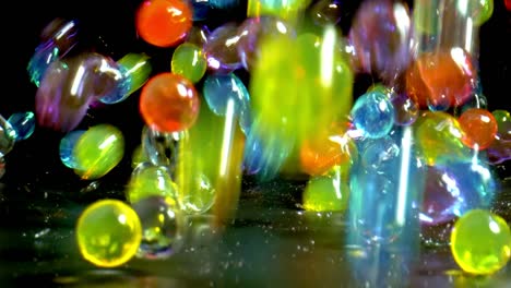 colorful bouncing glossy wet balls with reflection shot on black background