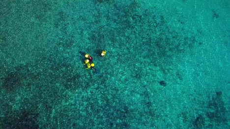 Aerial-view-of-two-people-holding-diving-bells-to-dive-with-an-aquatic-scooter-and-explore-the-seabed,-Pirate-Bay,-Curacao,-Dutch-Caribbean-island