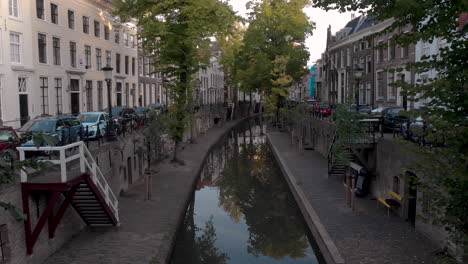 aerial early morning canal view of the nieuwe gracht in medieval dutch city of utrecht going over a bike locked on the bridge in the foreground revealing the lower level wharf