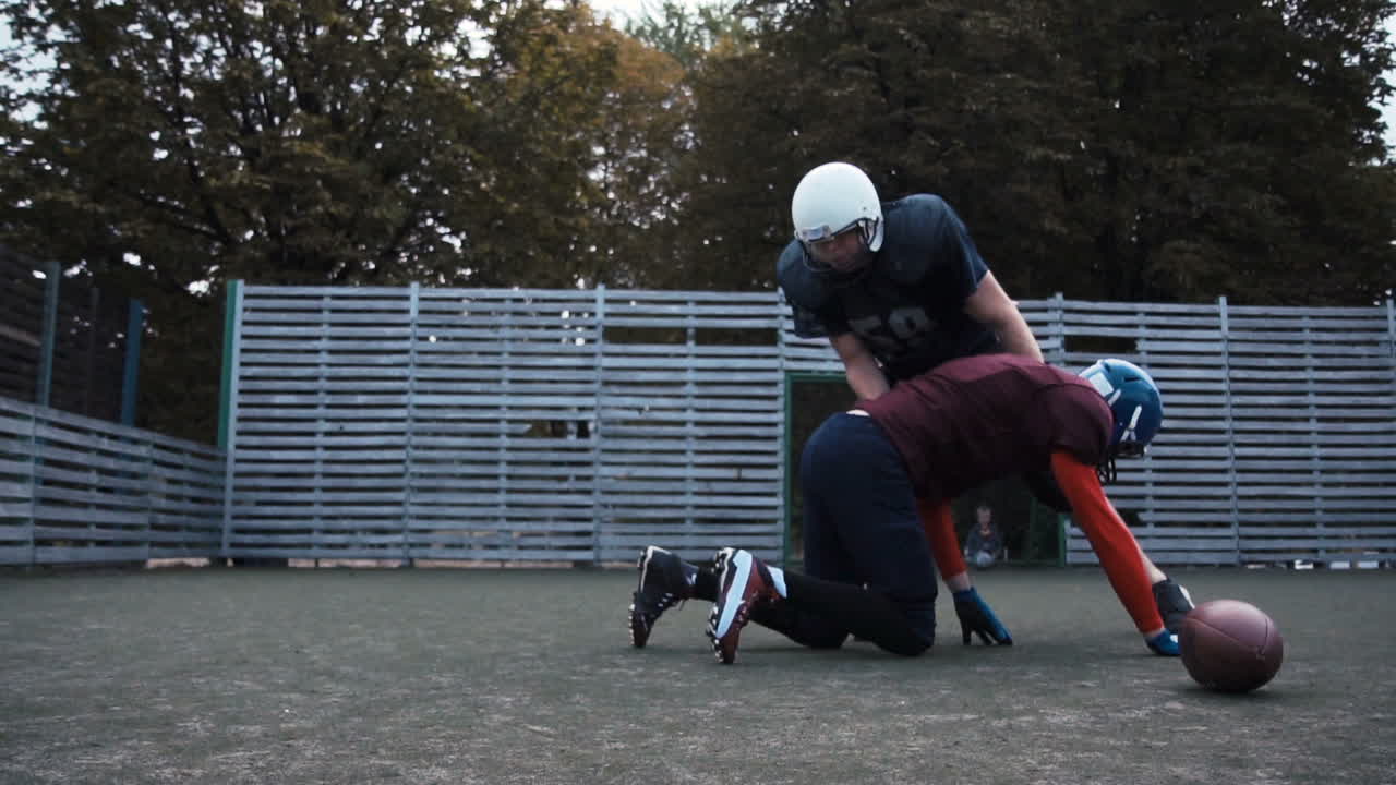 American Football Players Training and Tackling on a Field