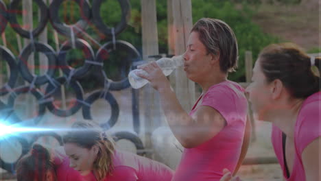 exercising outdoors, women in pink shirts with tire obstacle, one drinking water