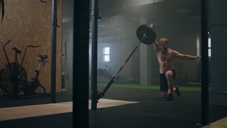 A-man-working-out-in-the-gym-pushes-a-landmine-bar-with-his-hand-while-standing-on-one-knee