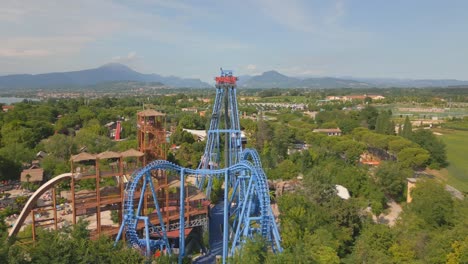 winding and twisting blue tracks of large roller coaster tower over amusement park by lake garda italy