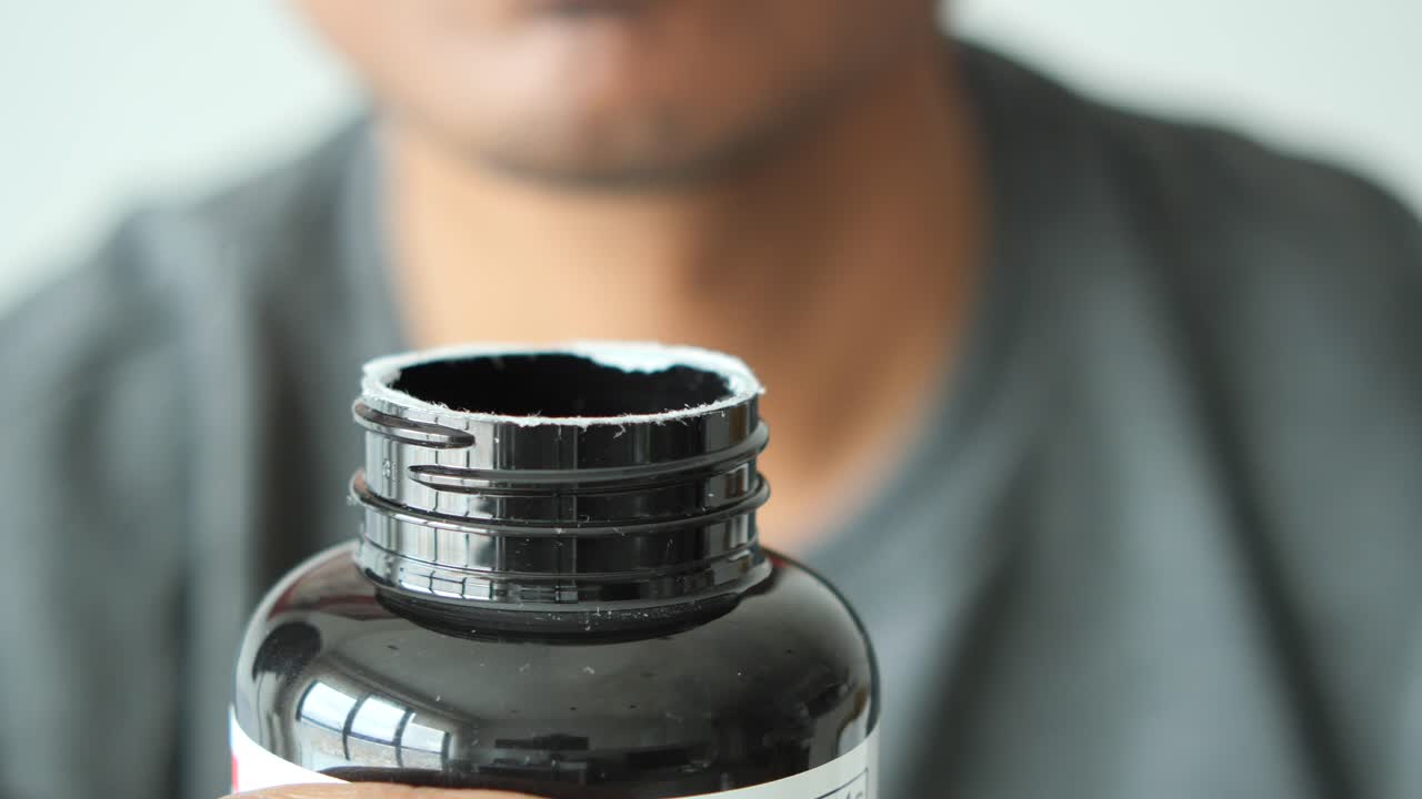 persona que abre una botella de suplemento negra