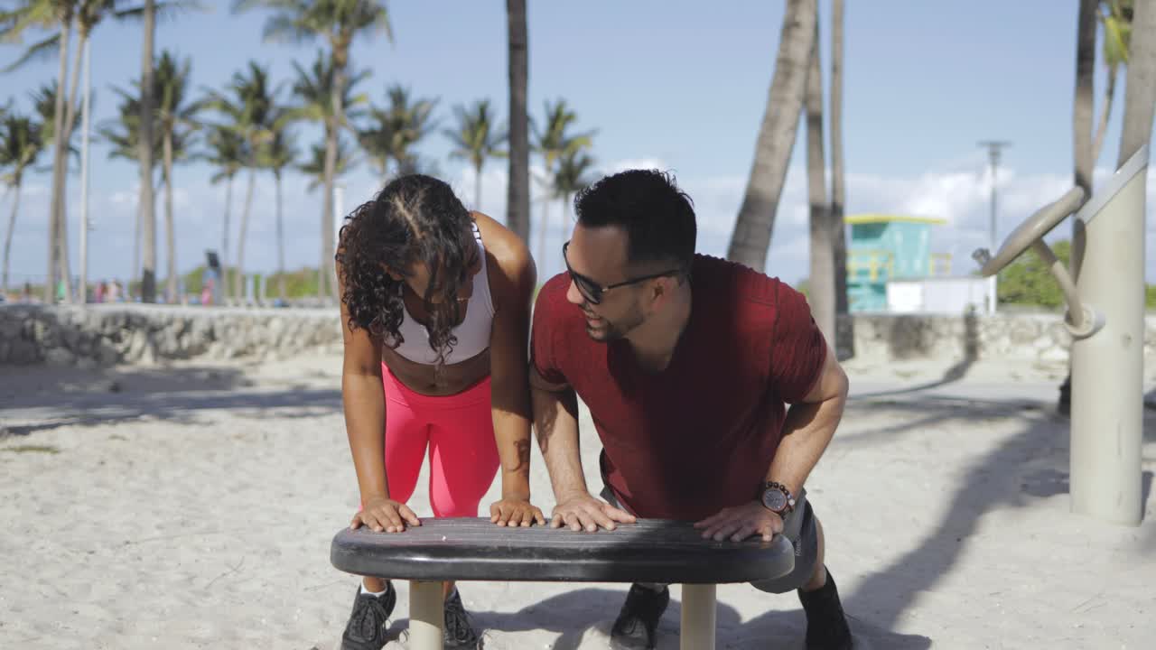 pareja deportiva riéndose entrenando en el gimnasio de la playa