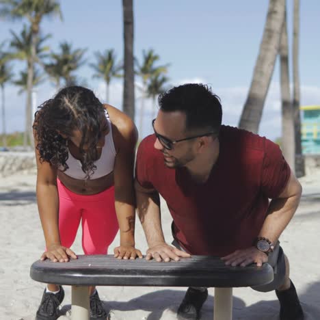 Laughing-sporty-couple-training-in-beach-gym-
