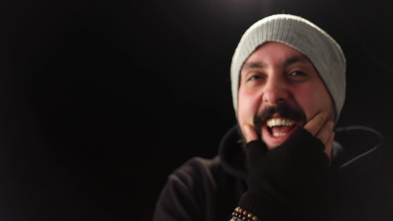 Happy young stylish man smiling and load laughing in front of camera isolated on a black background