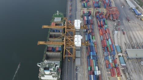 piccola barca che naviga oltre il porto dei container