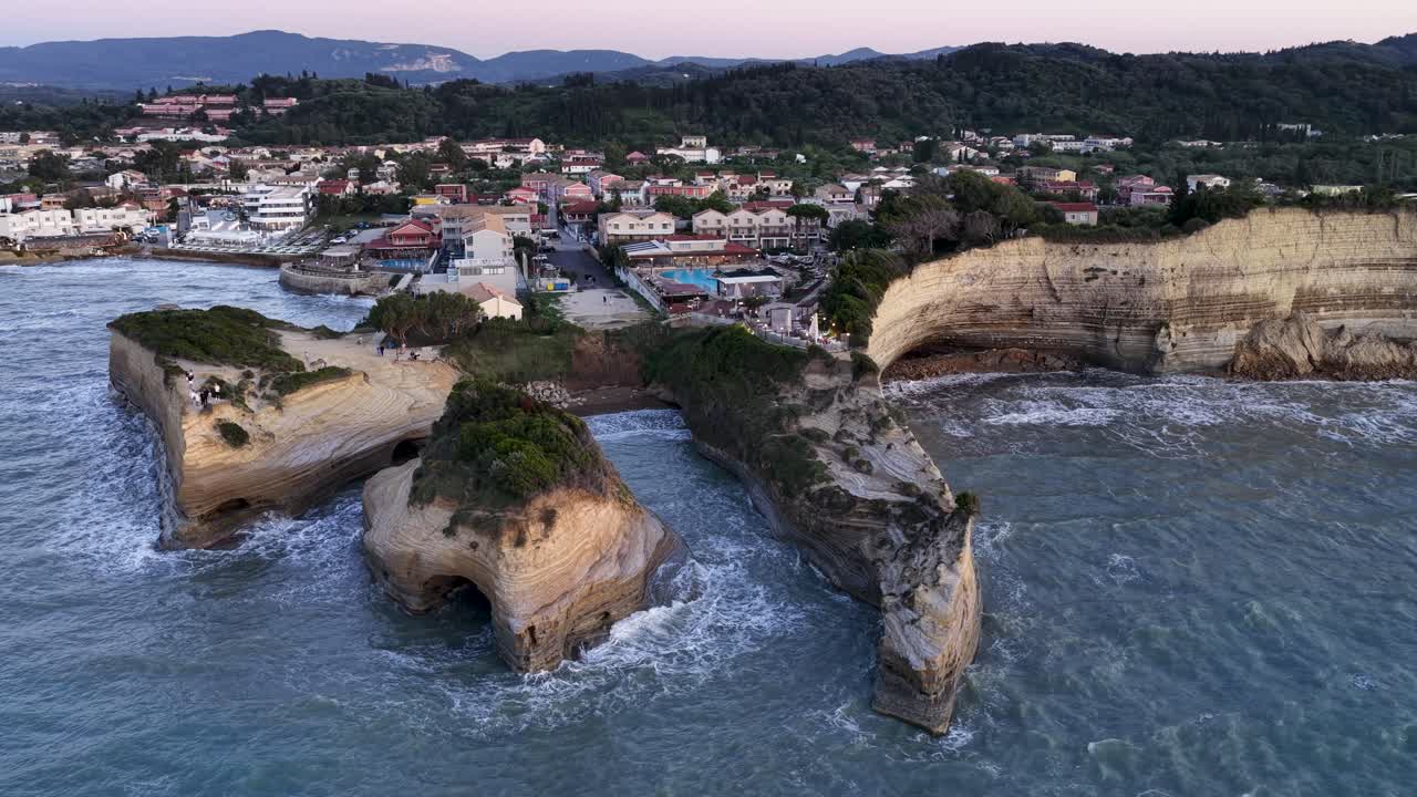 Corfu's Canal d'Amour at Dusk: An enchanting aerial vista showcasing the unique sandstone cliffs, tranquil coves, and the charming coastal village as evening descends.