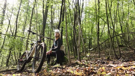 mtb athlete sit on tree stump and rest in green forest environment, czechia