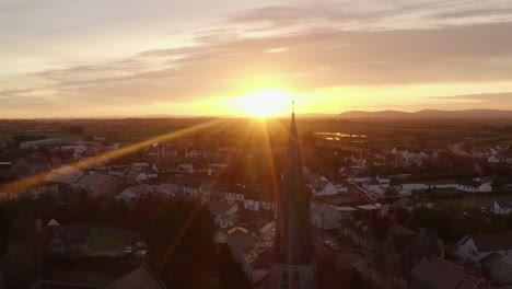 Cinematic aerial shot of Gort during sunset with Saint Colman's Church in the foreground