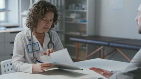 female doctor writing prescription during patient consultation in medical office