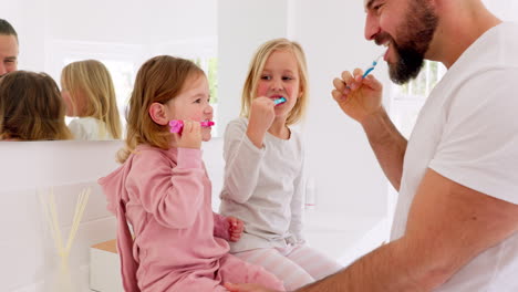 el padre ayuda a las hijas a cepillarse los dientes