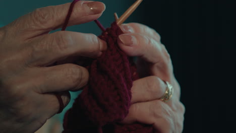 un primer plano de una mujer anciana hábil haciendo ganchillo a mano para su nieto.