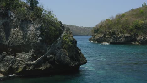 rock island in crystal bay of nusa penida bali during a sunny day surrounded by tropical water, aerial