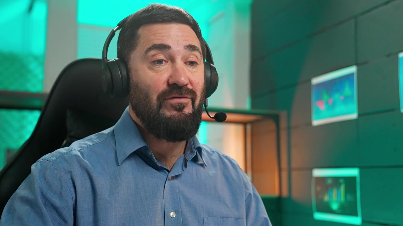 Uomo barbuto con cuffie che parla durante una videochiamata in un ufficio moderno