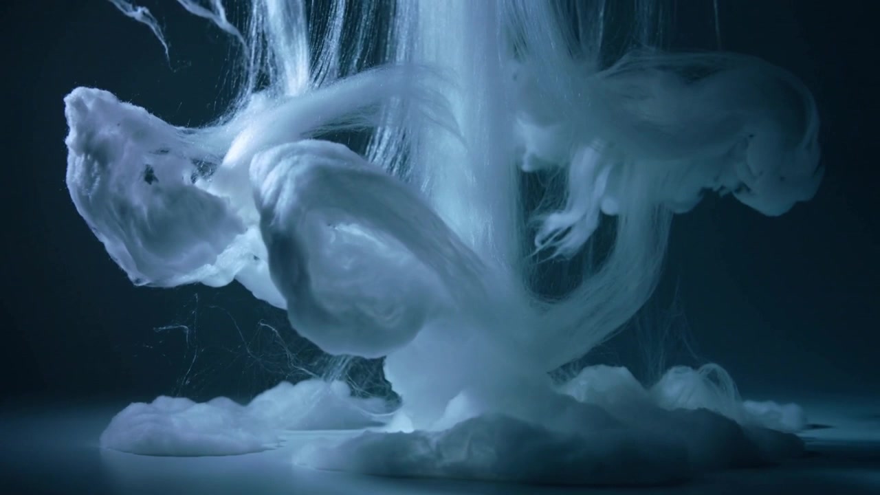 Nozzle injecting white pigment plume descending through studio tank, forming looping ribbons