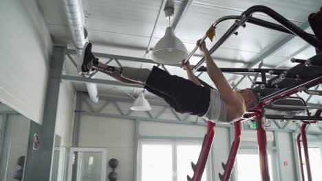 strong disabled athlete with prosthetic leg do hanging leg excercise at the gym