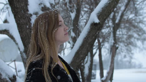 mujer feliz afuera en cámara lenta nieve de invierno como copos de nieve caen en cámara lenta cinematográfica