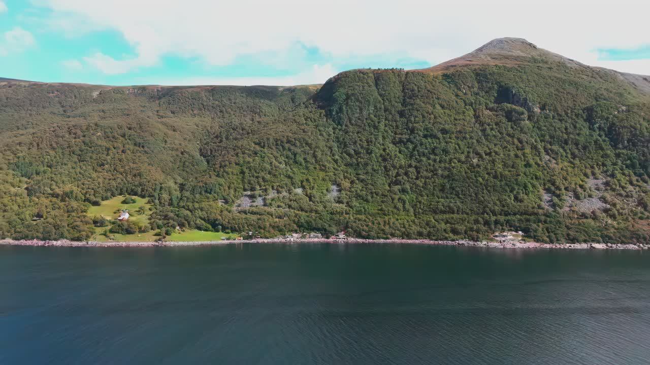 Aerial pan of the scenic Nøringset coastline in Norway, featuring lush green hills and calm waters