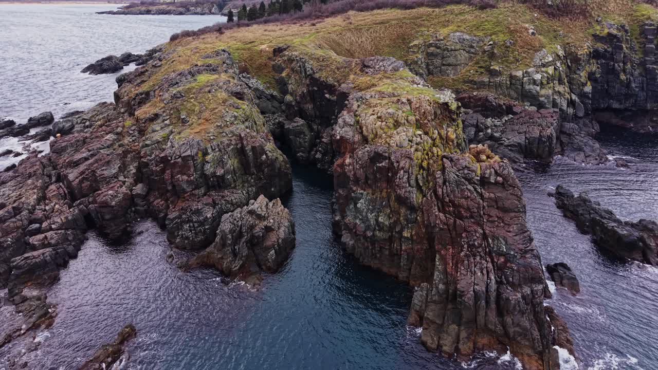 Costa rocciosa con acqua che circonda la terra e l'erba vicino alla costa