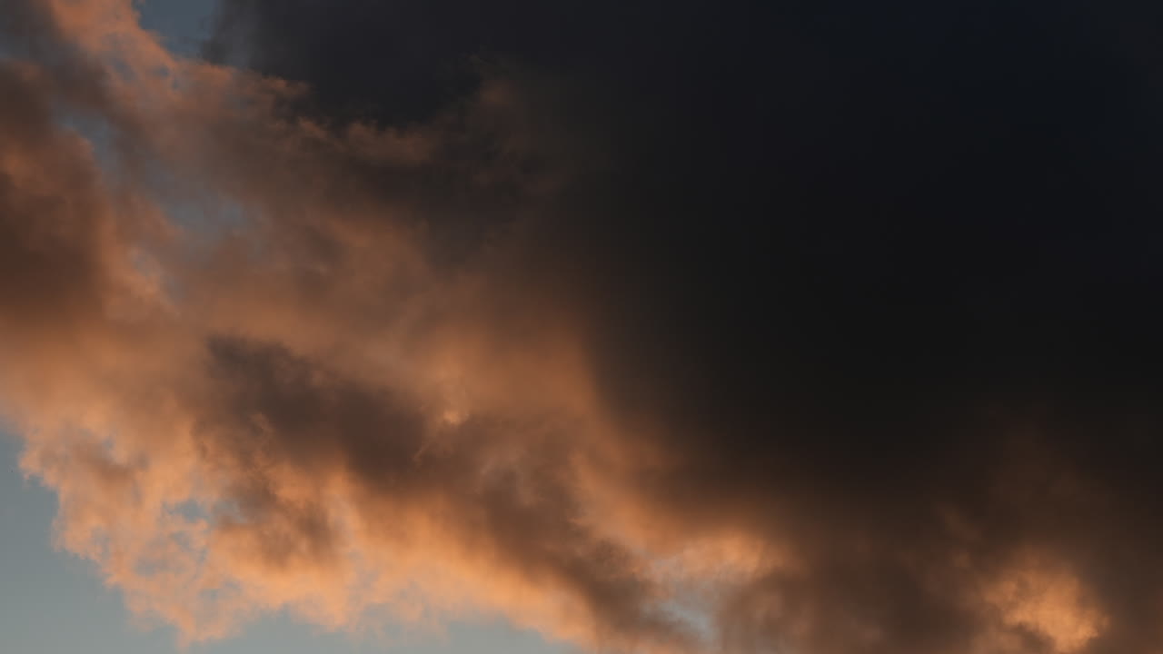 해가 지는 동안 하늘의 파란색 패치와 함께 움직이는 오렌지색 구름의 시간 경과