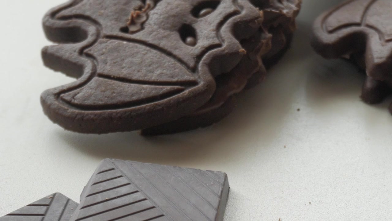 Biscotti a forma di pipistrello e pezzi di barrette di cioccolato - Dolcetti di Halloween - leggero movimento laterale della telecamera.