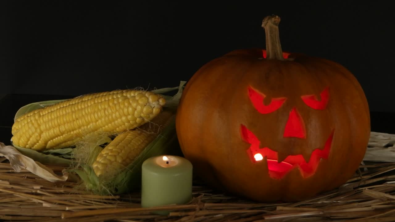 calabaza de halloween, vela ardiente y espigas de maíz, fondo negro, fiesta de halloween