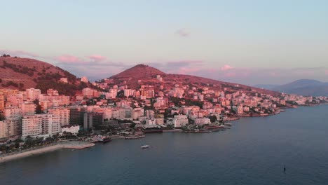 Antena-De-Rotación-Lenta-Sobre-La-Hermosa-Ciudad-De-Saranda-En-Albania-Al-Atardecer