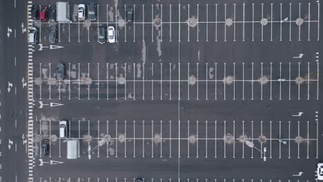 aerial: empty parking lot with only a few automobiles parked