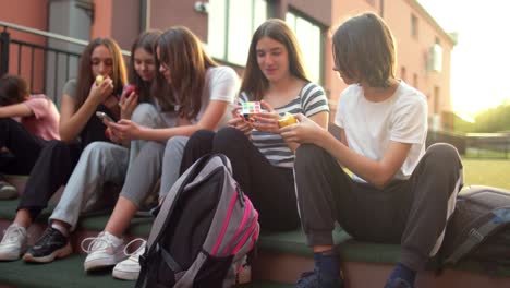 estudiantes adolescentes se divierten y conversan usando sus teléfonos móviles en el patio de la escuela
