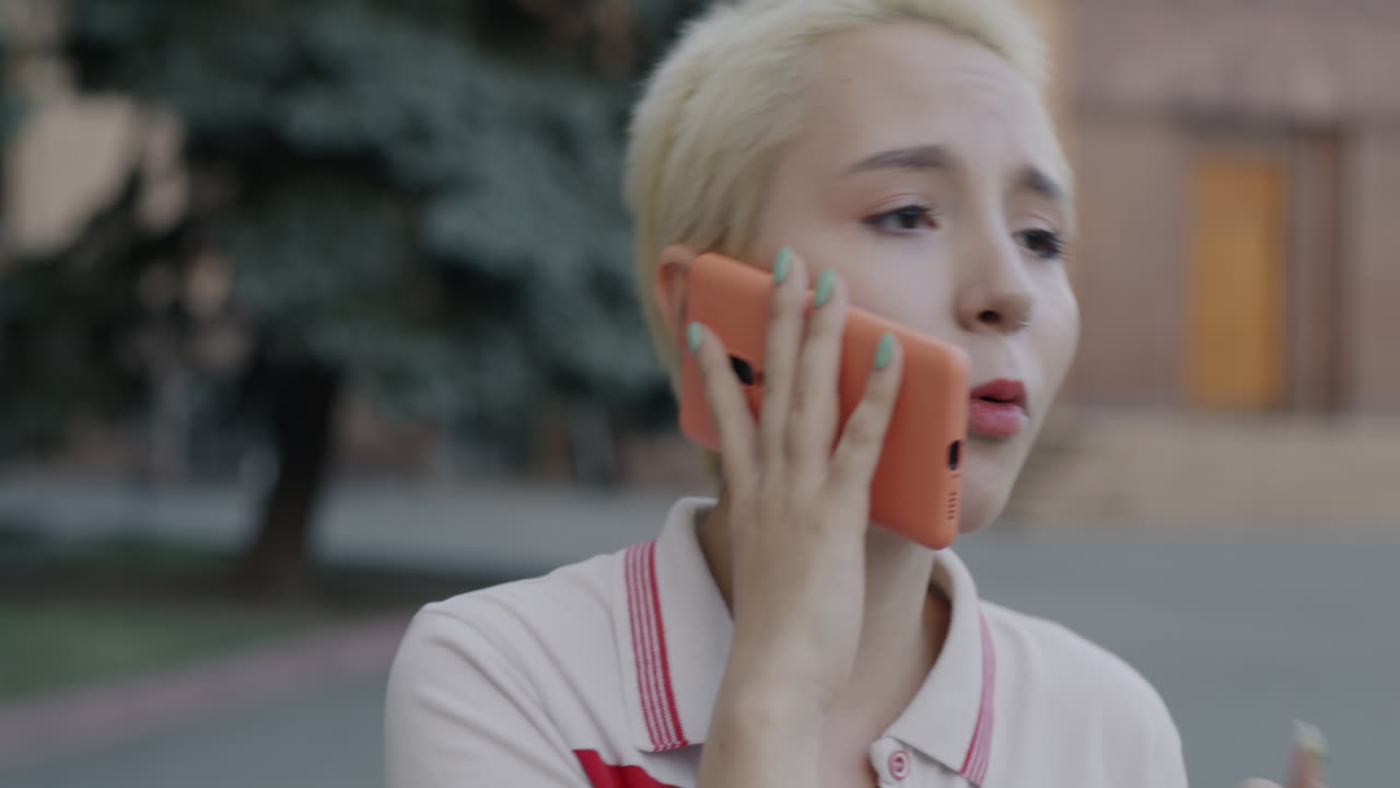 젊은 여성이 야외에서 전화로 이야기하고 있습니다.