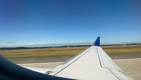 window view of passenger airline taking off from jfk airport amidst clear blue skies