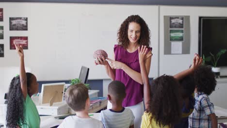 video of happy caucasian female teacher and diverse school children studying biology in classroom