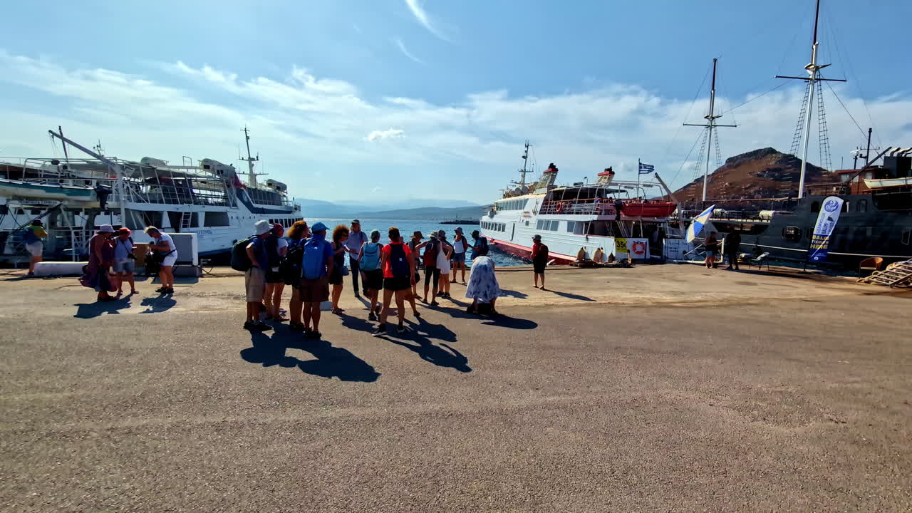 People gathering at a sunny port with various boats docked