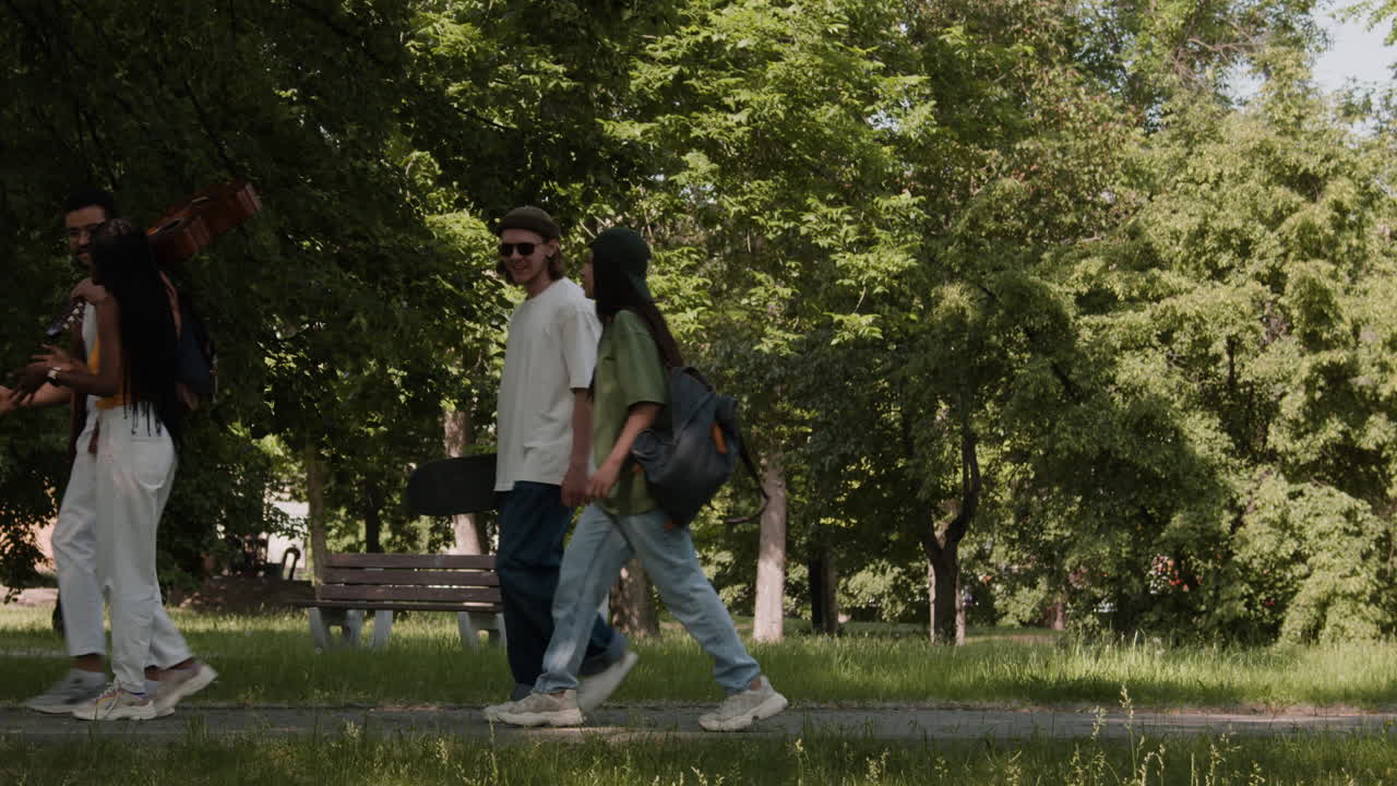 A group of friends walking and socializing in a park on a sunny day.