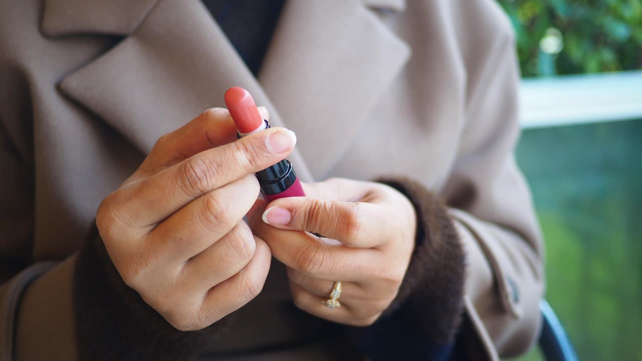 Primo piano delle mani di una donna che avvitano un tubetto di rossetto