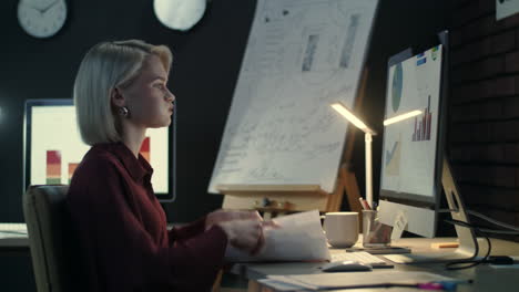 Focused-business-woman-checking-financial-reports-on-computer-in-dark-office