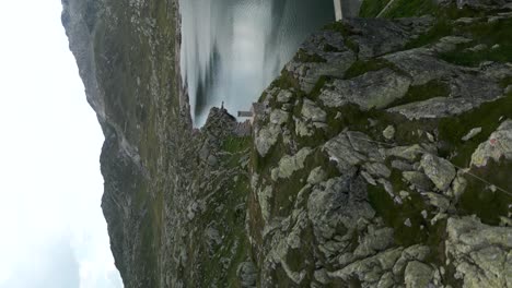 toma aérea ascendente de un acantilado rocoso junto al lago en el paso de grimsel