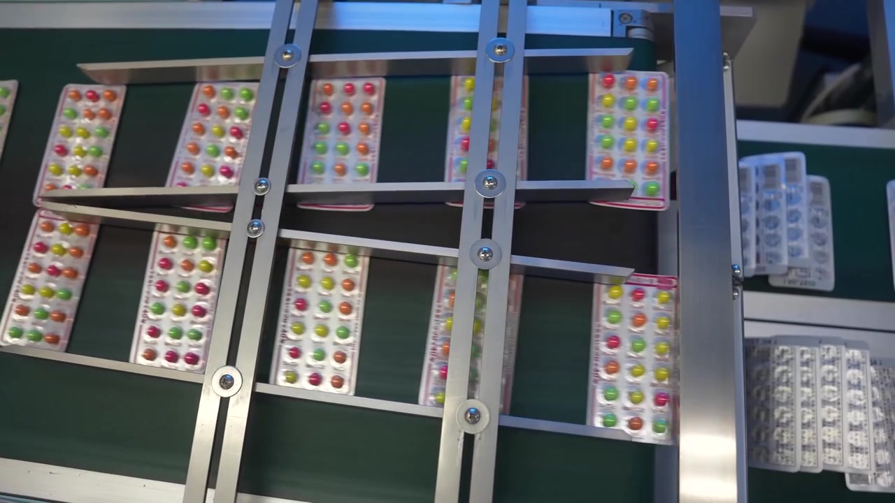 Blister packs filled with colorful round tablets moving along a packaging line