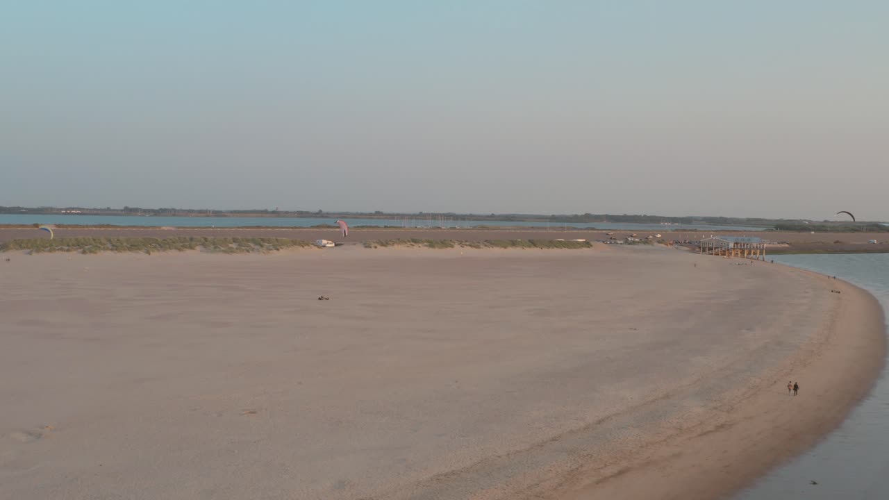 drone cinemático - panorama aéreo que rodea la playa de naturaleza verde y arenosa al atardecer con turistas y personas con buggykiting en zelanda en el mar del norte, países bajos, 30p