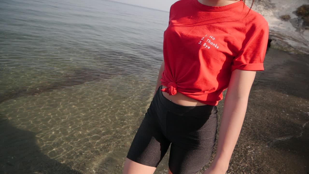 tiro de seguimiento de la hermosa modelo femenina dando un paseo por la orilla descalzo en cámara lenta