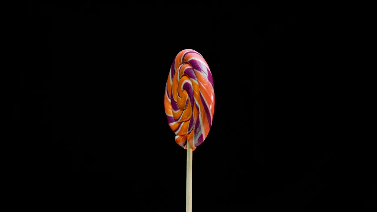 caramelo de piruleta girando sobre un fondo negro. espacio de copia en espiral de caña de caramelo