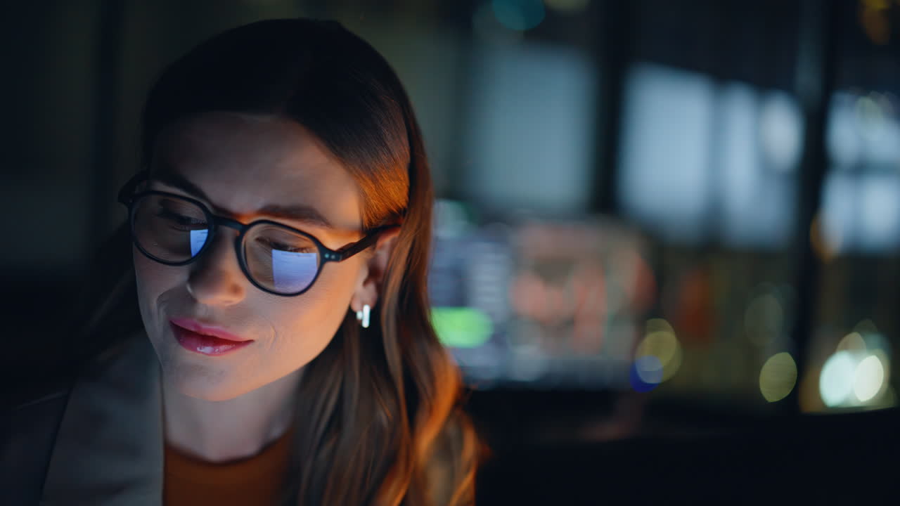 Woman stockbroker working late at night reviewing charts on computer closeup