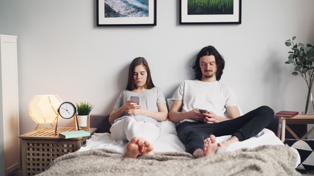 Couple Relaxing on Bed with Smartphones