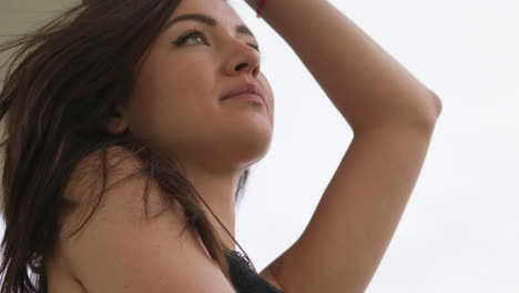 mujer joven de pie afuera en un balcón, el cabello atrapando el viento