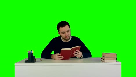 young and concentrated student reads a book on a green screen