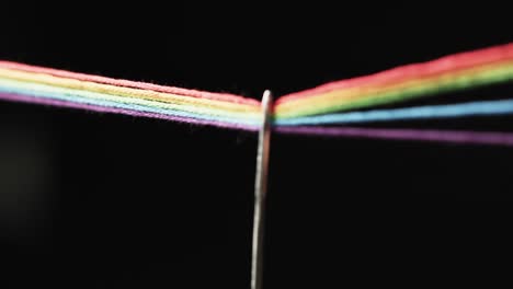 video de micro de hilos de color arco iris que pasan a través de la aguja con espacio de copia en fondo negro