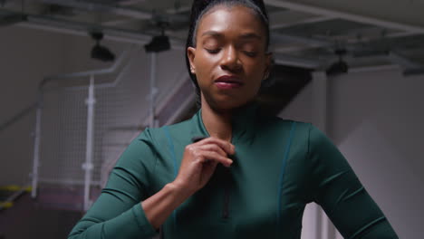 portrait of determined female athlete zipping up tracksuit training in gym stretching and warming up preparing for sports event 1