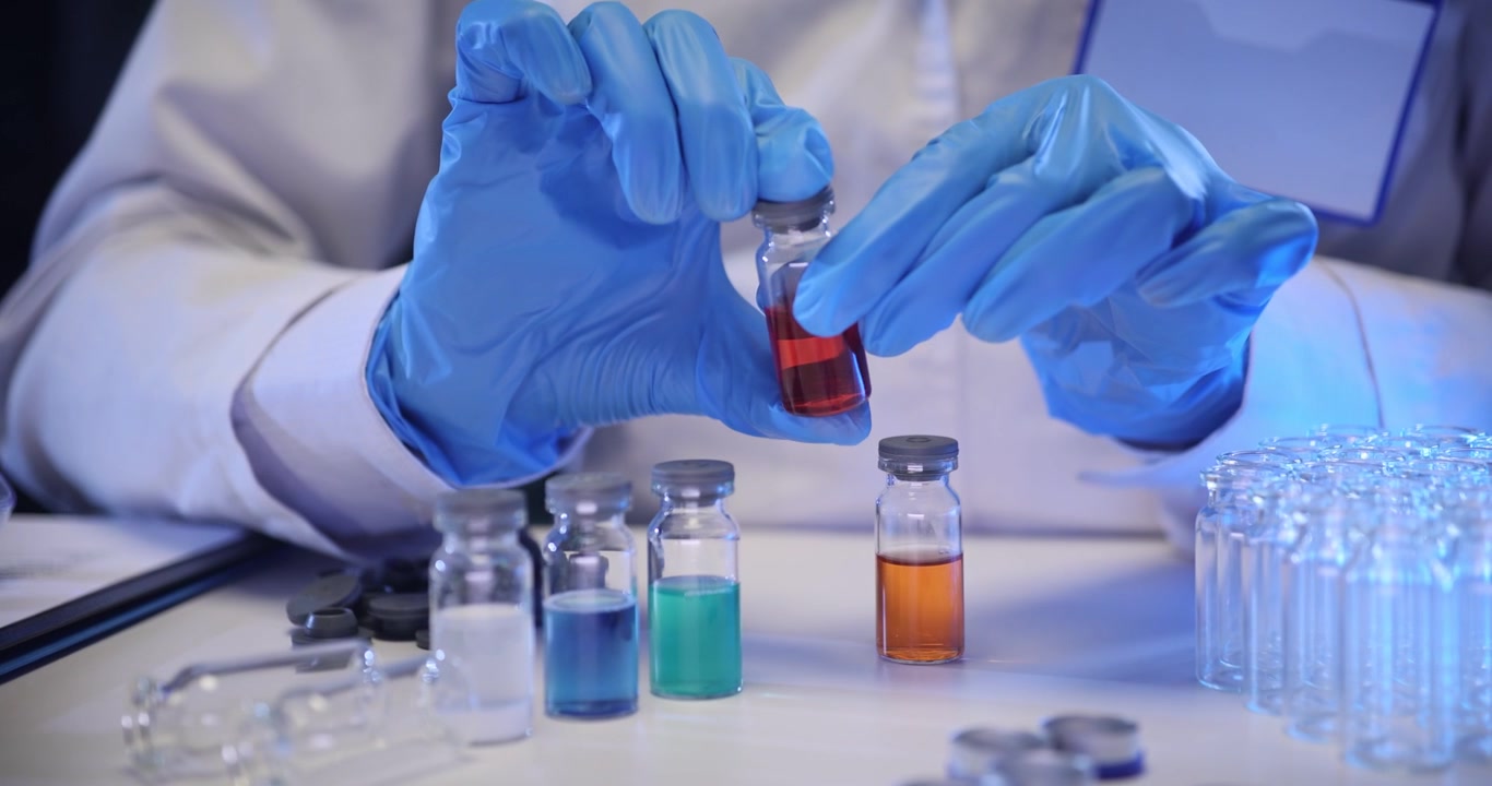 Lab worker closes caps on bottles filled with colorful liquids